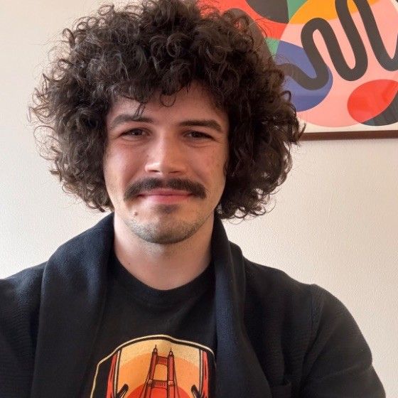 Simon Gagnon smiling, with curly dark hair and a moustache